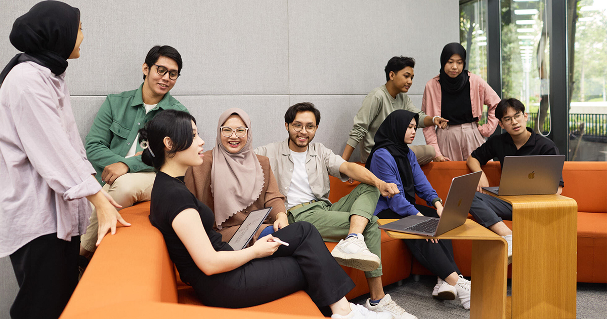 주황색 소파가 있는 라운지 공간에서 협업 중인 개발자들